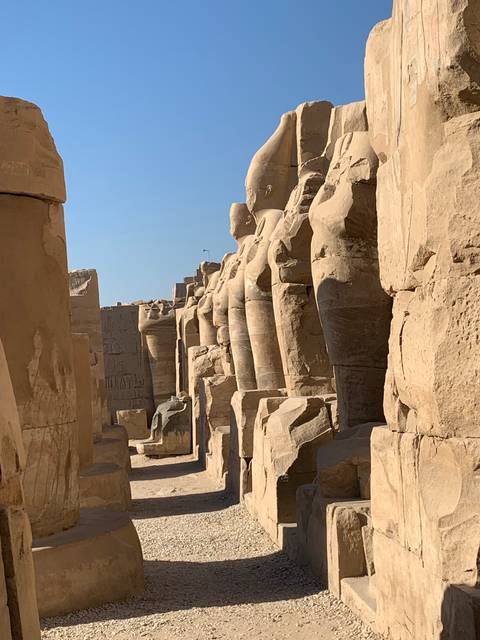       Series of ancient stone statues lined along a path.
  