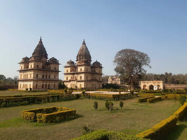       Two intricately designed temple towers in a landscaped garden.
  