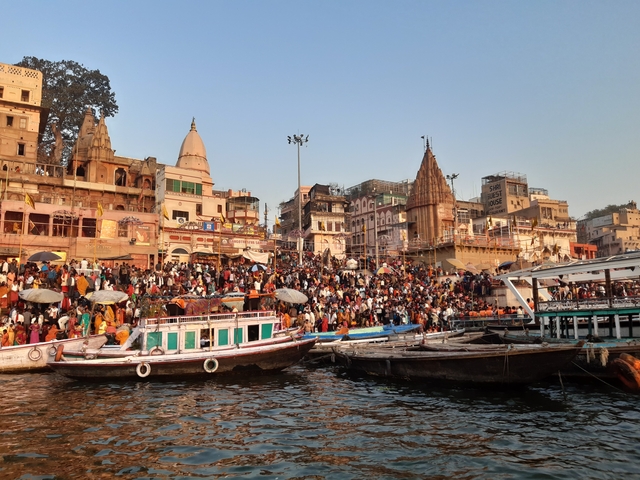 A bustling waterfront area with boats and a crowd.