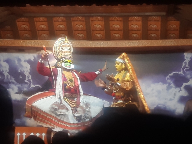       Kathakali performers on stage in vibrant costumes
  