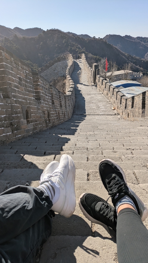 Stairs built on a historic wall with shoes visible in the foreground.