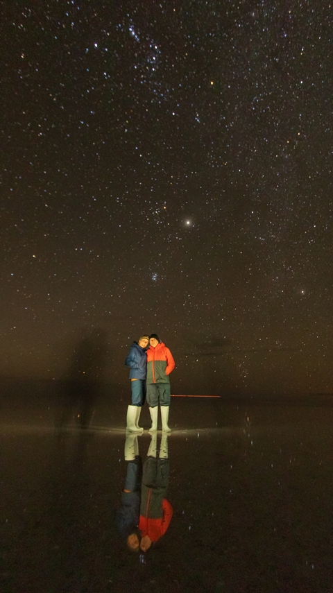 Two people standing under a starry night sky.