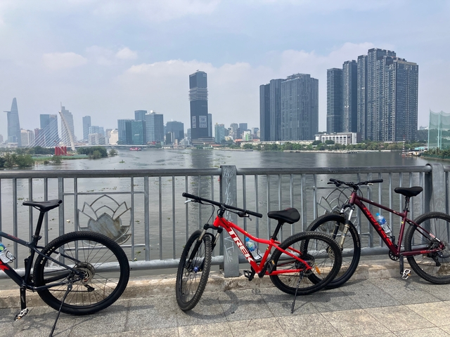 Bicycles parked in front of a river with a city skyline.