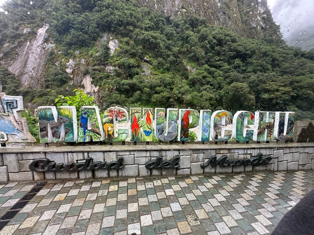 Colorful Machu Picchu sign with lush greenery.