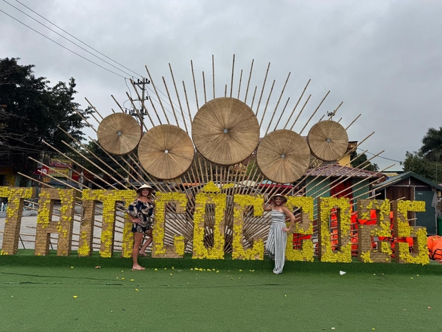 Two women posing in front of a large sign and decorative display.