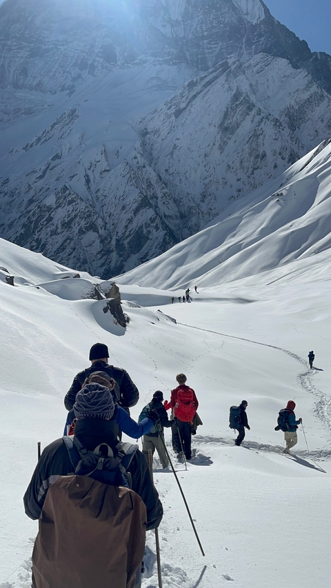 People trekking through a snowy mountain path.