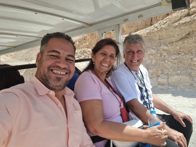 Three people sitting in a vehicle smiling at the camera.
