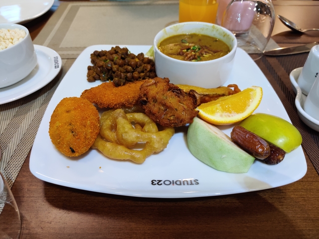 Plate of diverse foods served on a white plate with beverages.