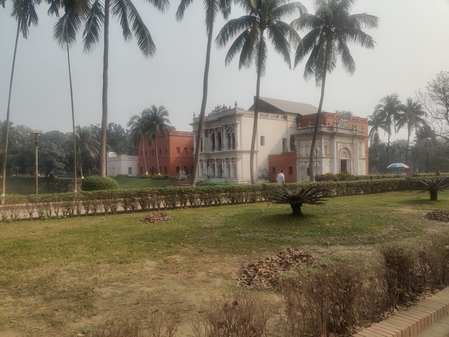 Colonial-style building with manicured lawns and palm trees.