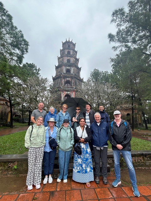 Group of tourists in front of a historic tower with decorative architecture.