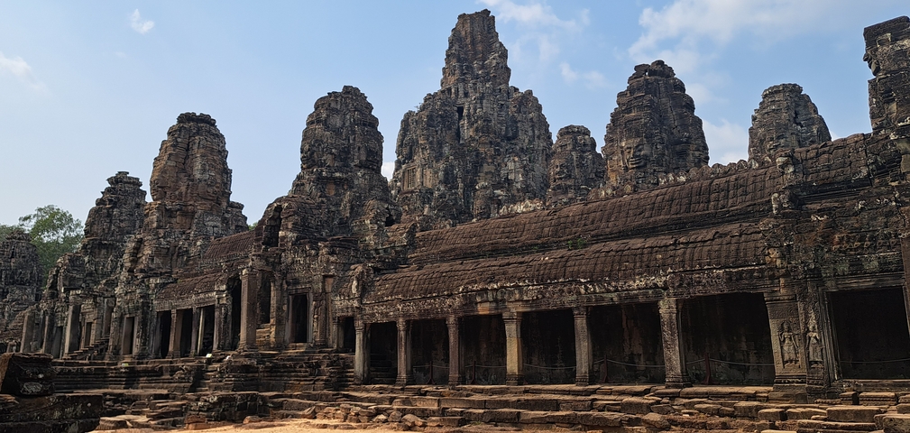 Ancient temple ruins with multiple stone towers against a blue sky.