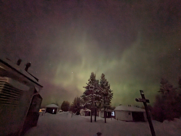 Northern lights over a snow-covered cabin area.