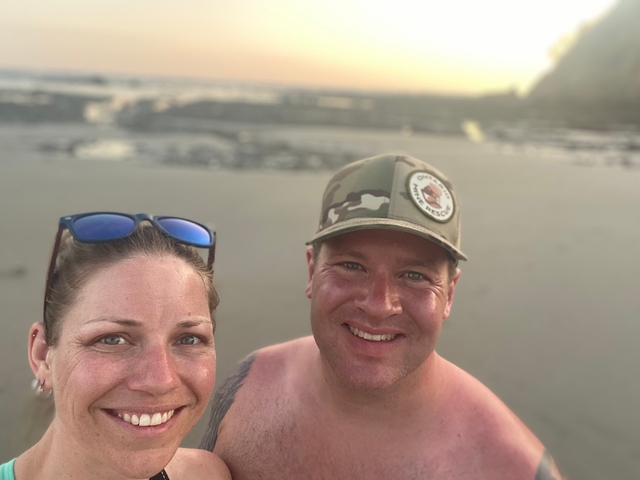 Couple posing on a beach during sunset.