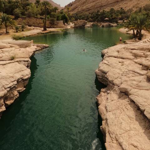 A person swimming in a natural rock pool.