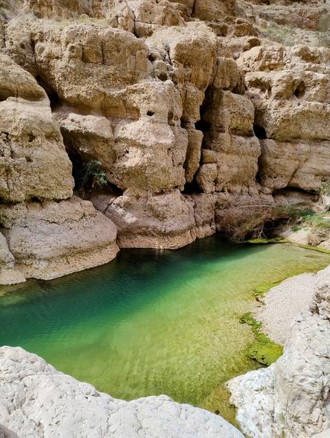 A natural pool with clear water against rocky cliffs.