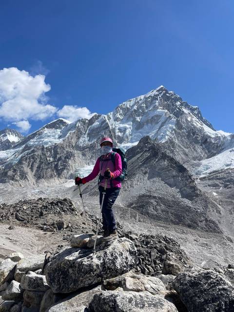 A person posing with a snowy mountain peak in the background.