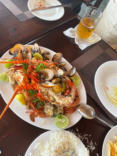 Seafood platter with clams, prawns, and lime wedges.
