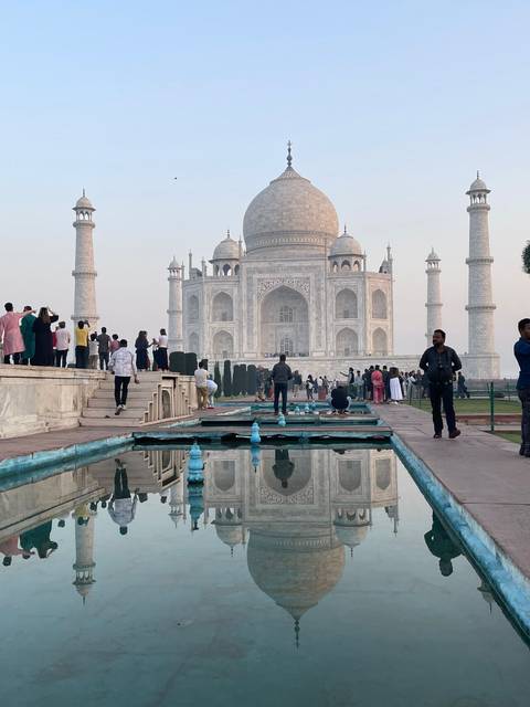       The Taj Mahal with reflection in the foreground pool at sunrise.
  