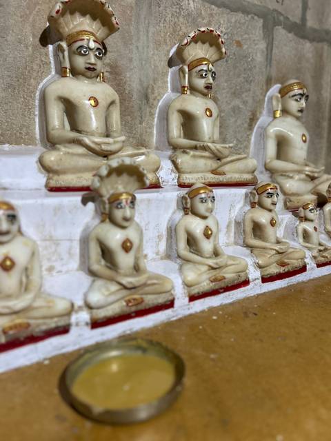       Small statues of seated figures in a row.
  
