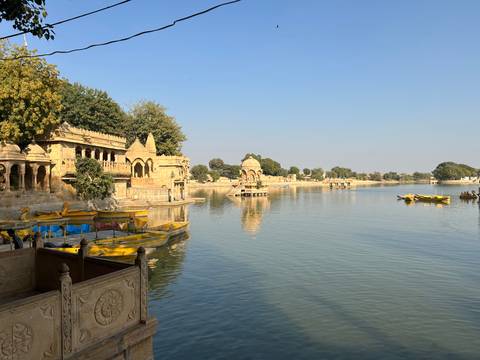       A tranquil lake with historical architecture and boats.
  