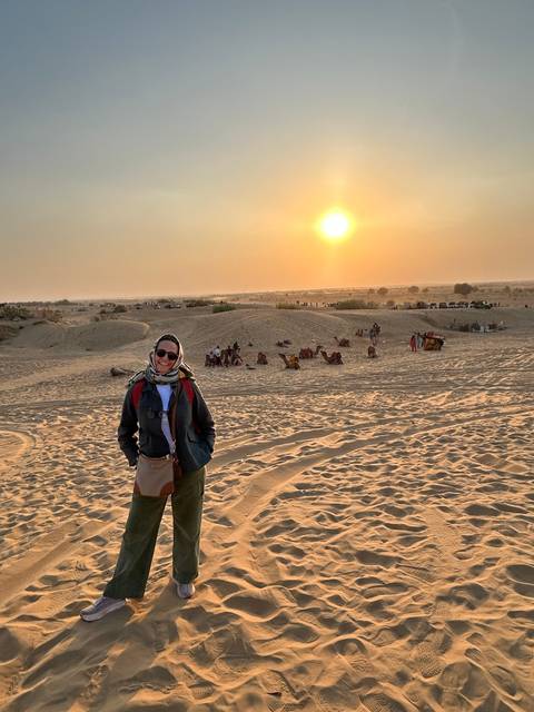       A person posing in the desert at sunset.
  