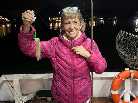       Person holding a fishing catch on a boat at night.
  