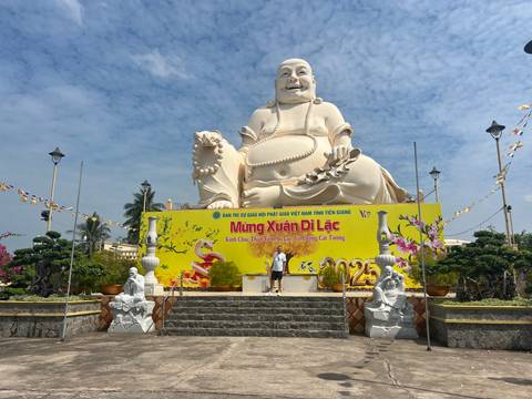       A large Buddha statue with decorative signs.
  