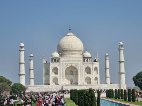 The Taj Mahal with a clear blue sky and tourists below.