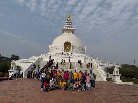 Large group posing in front of a large white stupa.