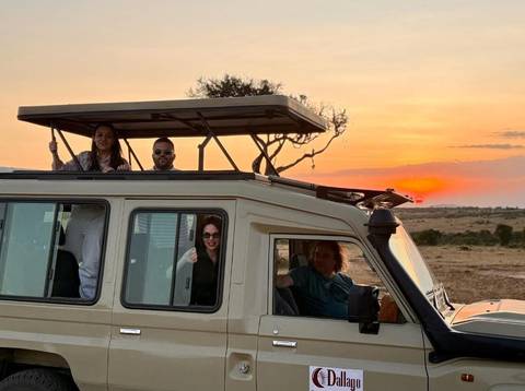Safari vehicle with tourists at sunset.