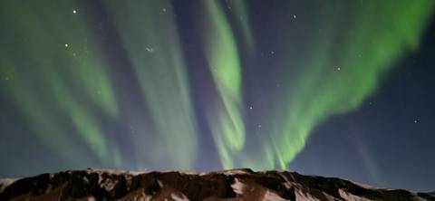       Northern lights over a snow-covered mountain.
  