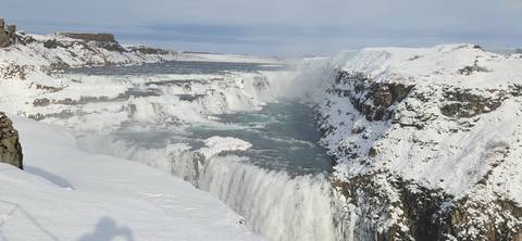       Snow-covered waterfall flowing into a river below.
  