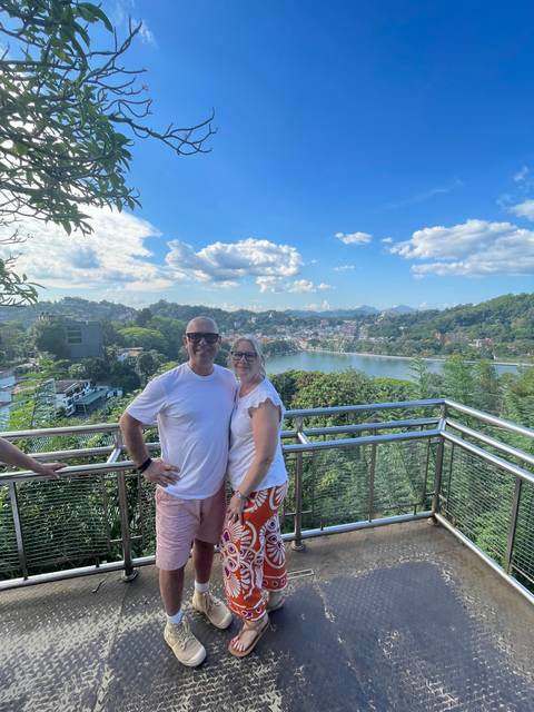 Couple posing on a balcony with city and lake view.