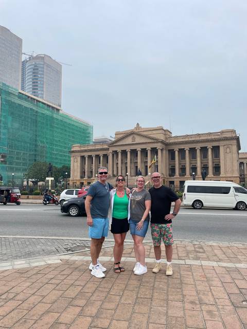       Group of four posing outside a historic building.
  