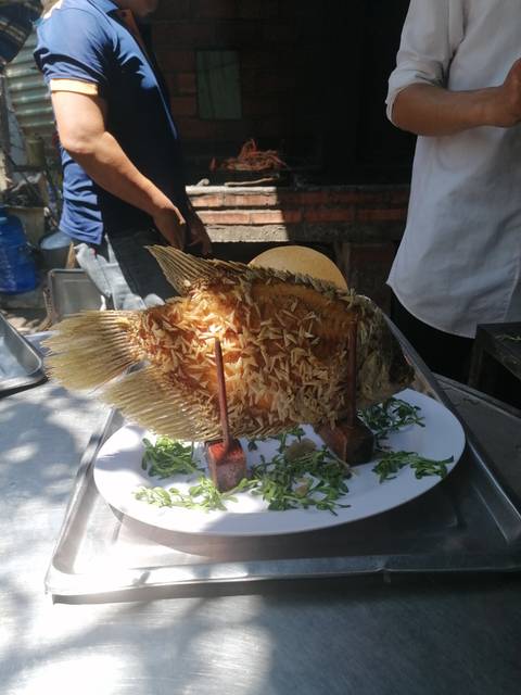 Fried fish on a dish with green garnishes.