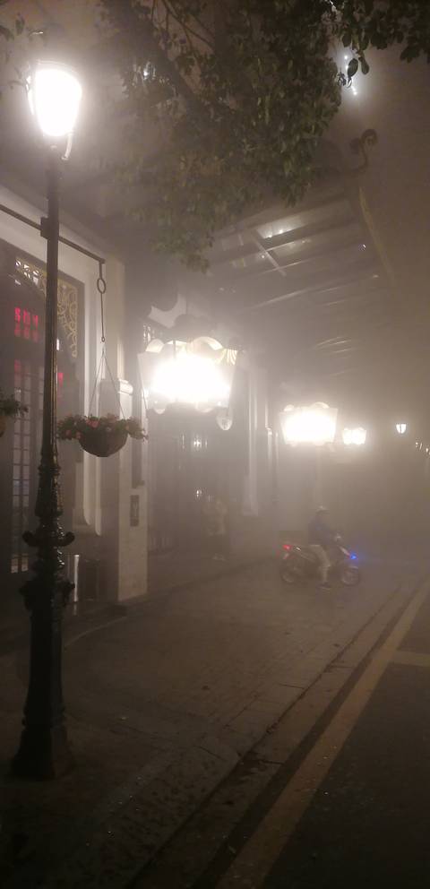 Foggy street scene with bright lights and parked motorbikes.