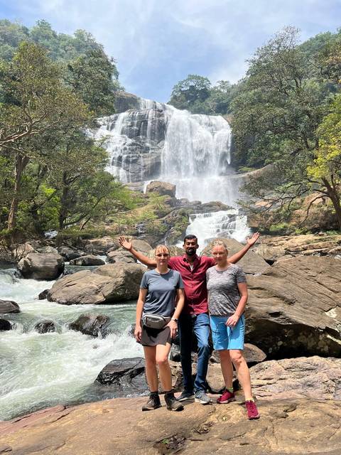 Three people posing in front of a waterfall.