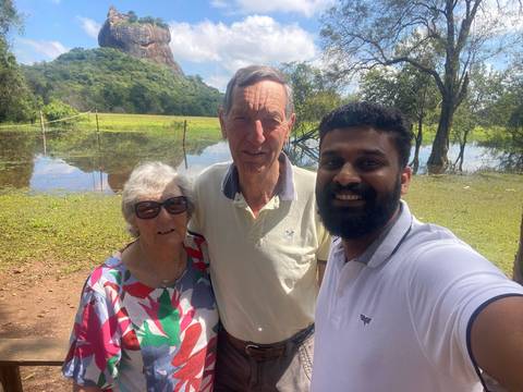 Group of people posing outdoors with a lake and rocks.