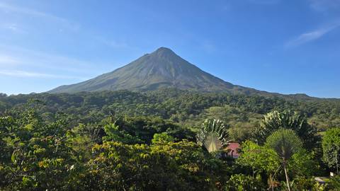 View of Arenal Volcano with a lush green forest in the foreground.