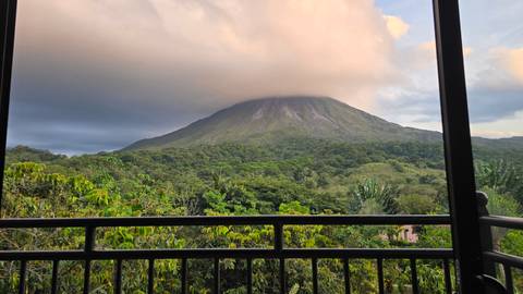 Arenal Volcano shrouded in clouds, viewed from a balcony.