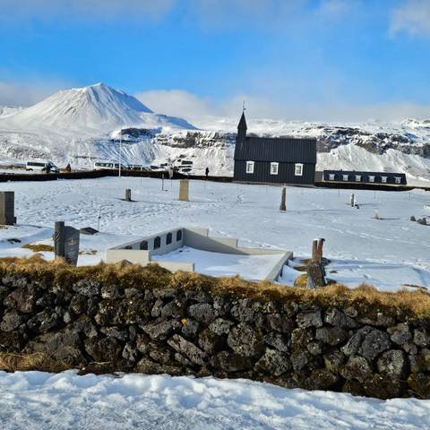       A cemetery and church in a snowy landscape.
  