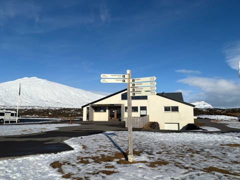       Information sign with snowfield and mountain backdrop.
  