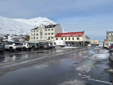       A snowy town square with parked cars and iconic hotel facade.
  