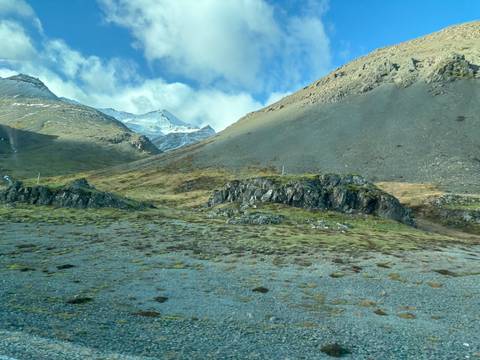       Icelandic landscape with hills, rocks, and patches of snow.
  