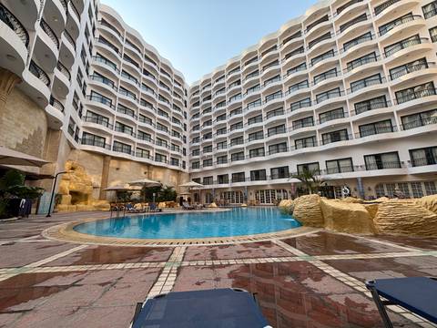 Hotel pool area with a large building in the background.