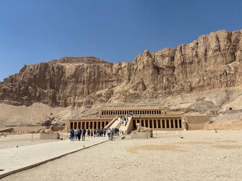 Tourists visiting a grand stone temple with steep stairs.