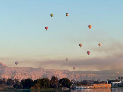       Several hot air balloons floating over a mountain range.
  