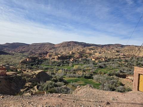 Wide view of a valley with green patches and hills.
