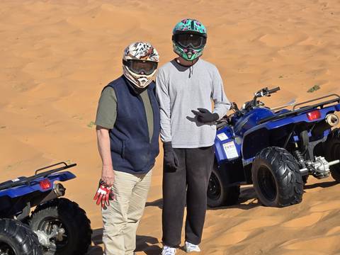 Two people with ATVs in a desert.