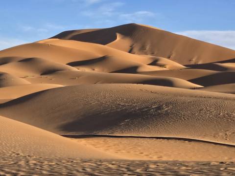       Smooth sand dunes under a blue sky.
  